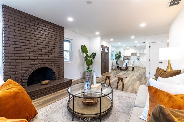 living room with light wood-type flooring and a brick fireplace