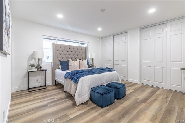 bedroom featuring two closets and light hardwood / wood-style flooring