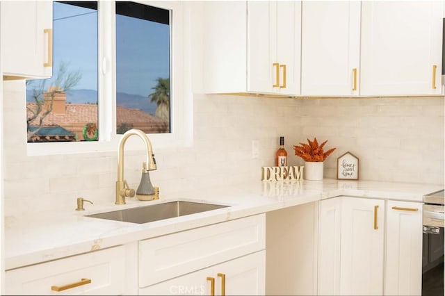 kitchen with sink, light stone counters, white cabinets, and tasteful backsplash