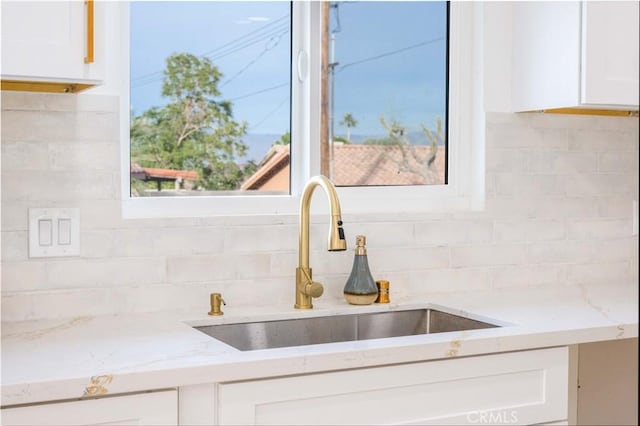 kitchen featuring sink, white cabinets, decorative backsplash, and light stone counters