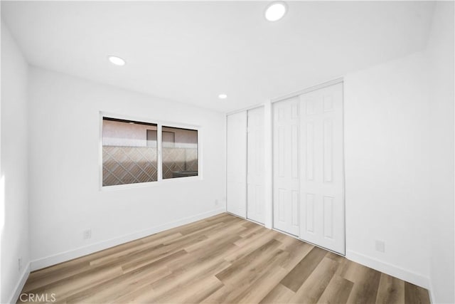 unfurnished bedroom with hardwood / wood-style flooring and multiple closets