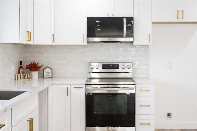 kitchen with light stone counters, white cabinets, decorative backsplash, and appliances with stainless steel finishes