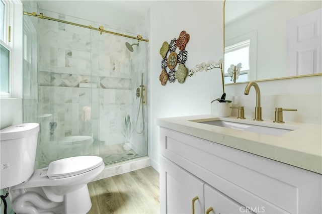 bathroom featuring toilet, vanity, an enclosed shower, and hardwood / wood-style flooring