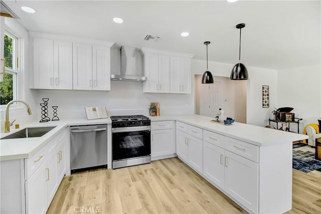 kitchen featuring stainless steel appliances, sink, kitchen peninsula, and wall chimney range hood