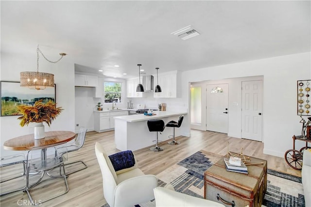 living room with a chandelier, light hardwood / wood-style flooring, and sink