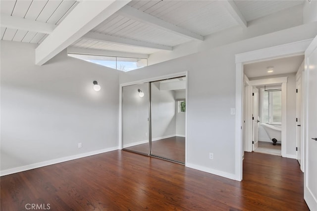 unfurnished bedroom with dark wood-type flooring, lofted ceiling with beams, a closet, and wood ceiling