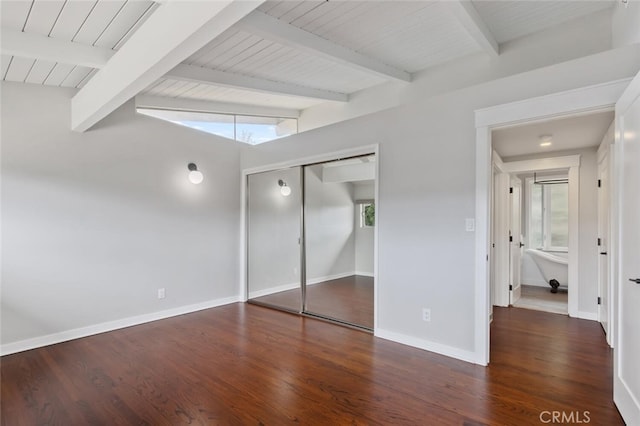 unfurnished bedroom featuring beamed ceiling, wood finished floors, a closet, baseboards, and wood ceiling