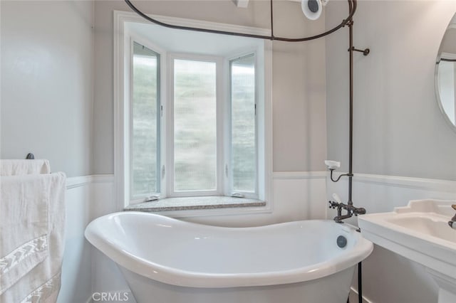 full bath with wainscoting, a healthy amount of sunlight, and a freestanding bath