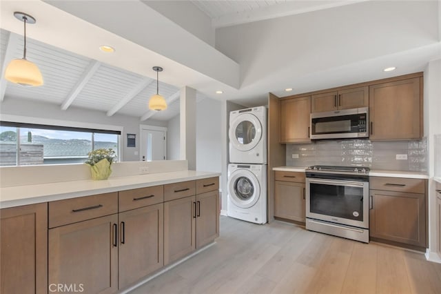 kitchen featuring hanging light fixtures, backsplash, light wood-type flooring, stacked washer and clothes dryer, and stainless steel appliances