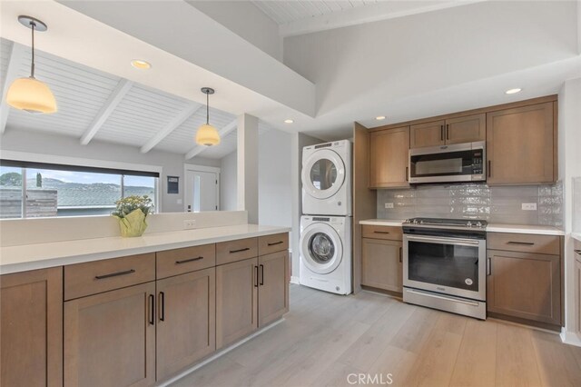 kitchen with appliances with stainless steel finishes, pendant lighting, lofted ceiling with beams, decorative backsplash, and stacked washer and dryer