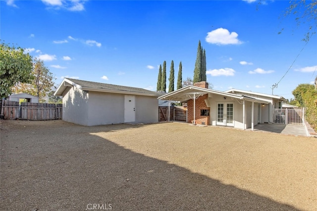 back of house with a chimney, french doors, fence, and stucco siding