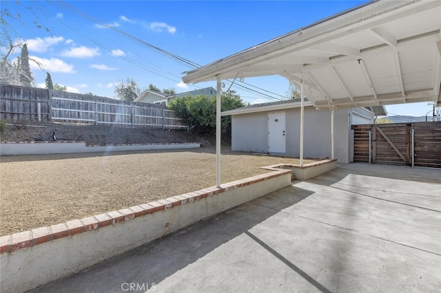 view of patio featuring a carport, a gate, and fence