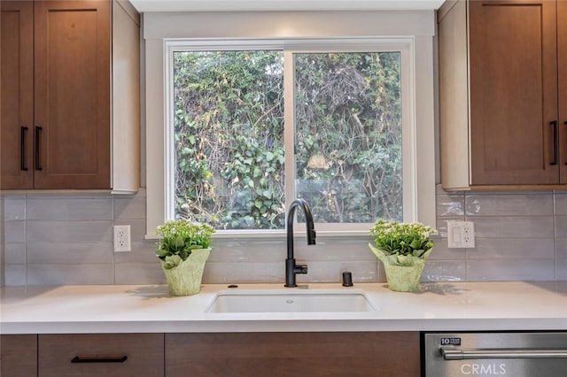 kitchen featuring a sink, light countertops, dishwasher, tasteful backsplash, and brown cabinets