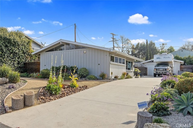 view of front of home with a garage, board and batten siding, an outdoor structure, and fence