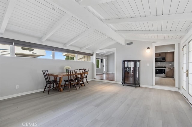 dining area with lofted ceiling with beams and light wood-type flooring