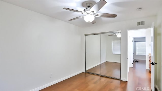 unfurnished bedroom featuring a closet, hardwood / wood-style floors, and ceiling fan