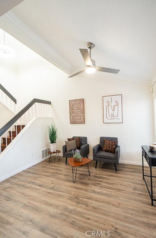 living area with ceiling fan, ornamental molding, and wood-type flooring