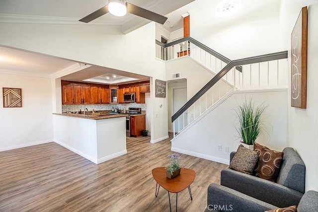 living room with ceiling fan, crown molding, and light wood-type flooring