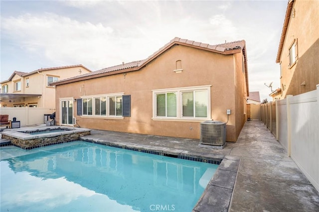 rear view of property with a patio area, a pool with hot tub, and central AC unit