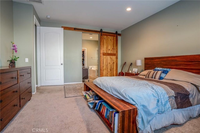 carpeted bedroom with ensuite bathroom and a barn door