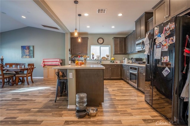 kitchen with decorative light fixtures, light hardwood / wood-style floors, a center island, a kitchen breakfast bar, and stainless steel appliances