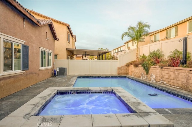 view of swimming pool with central AC and an in ground hot tub