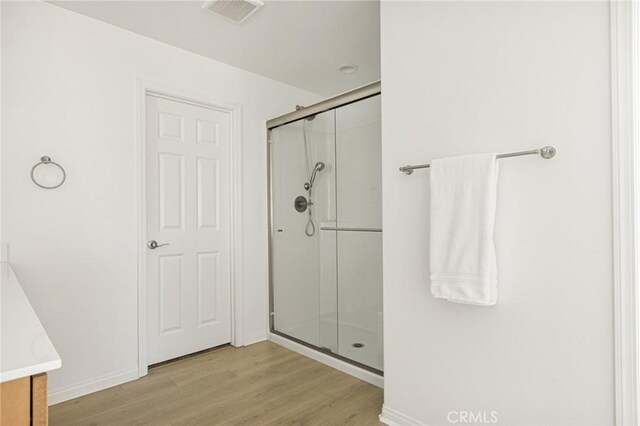 bathroom featuring a shower with shower door, vanity, and hardwood / wood-style floors