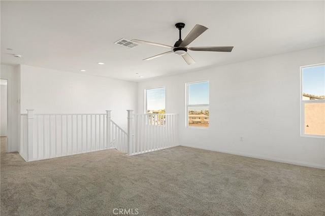 empty room featuring ceiling fan and light colored carpet