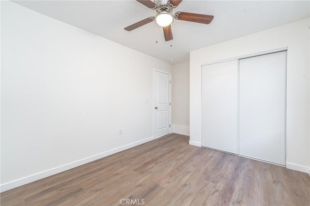 unfurnished bedroom with ceiling fan, a closet, and light hardwood / wood-style floors