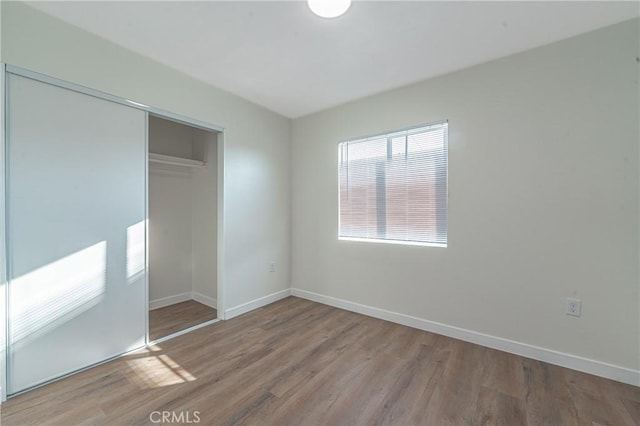 unfurnished bedroom with a closet, multiple windows, and light hardwood / wood-style floors