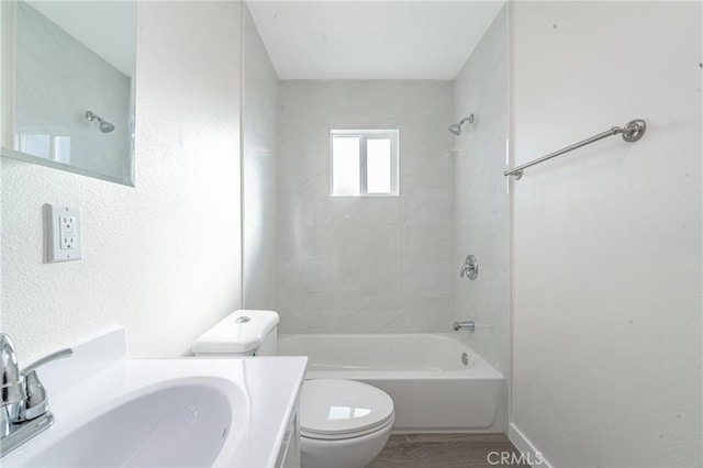 full bathroom with toilet, tiled shower / bath, vanity, and hardwood / wood-style floors