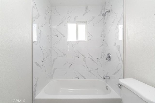 bathroom featuring toilet and tiled shower / bath