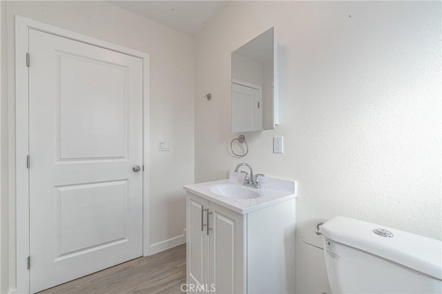 bathroom with toilet, wood-type flooring, and vanity