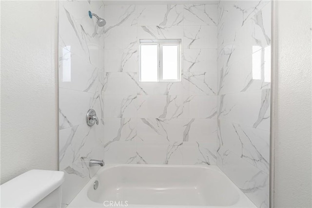 bathroom featuring toilet and tiled shower / bath