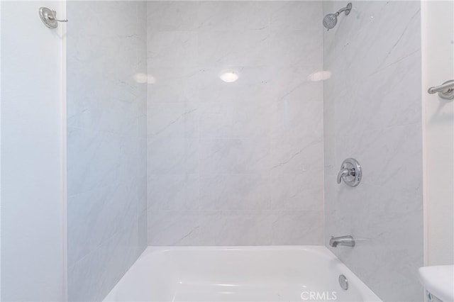 bathroom featuring toilet and tiled shower / bath combo