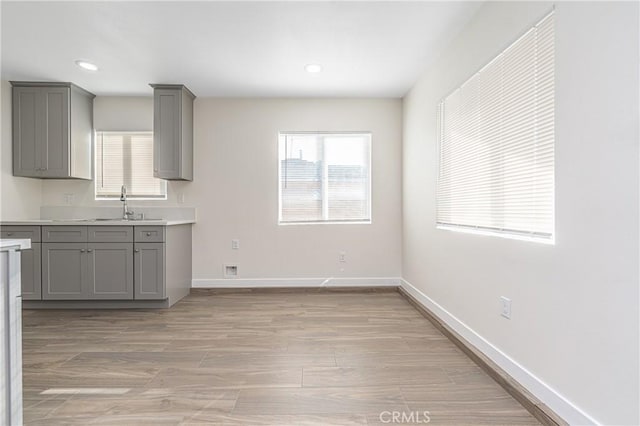 kitchen with sink, gray cabinets, and light wood-type flooring