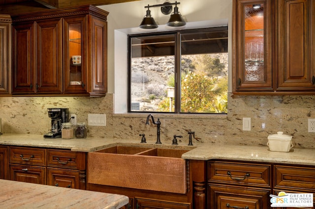 kitchen featuring light stone countertops, decorative backsplash, and sink