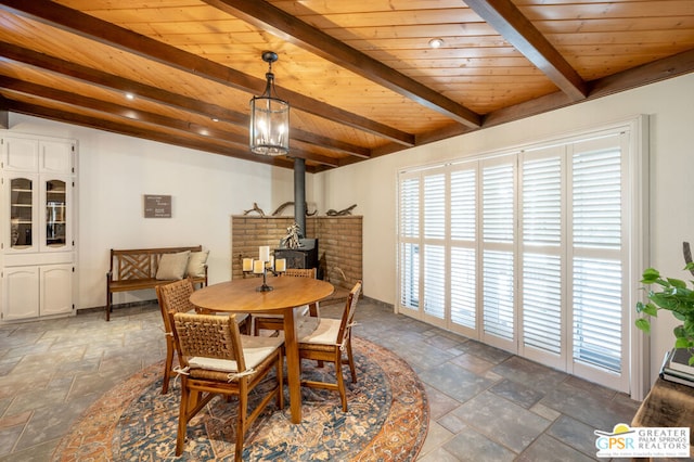 dining space with beam ceiling, a wood stove, and wooden ceiling