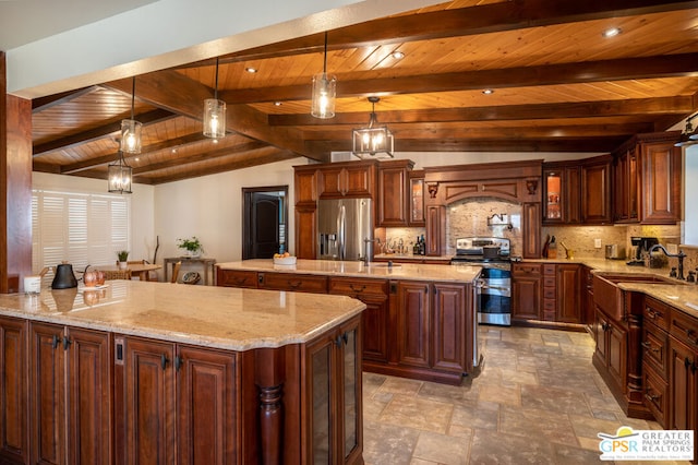 kitchen featuring sink, pendant lighting, appliances with stainless steel finishes, and a center island with sink