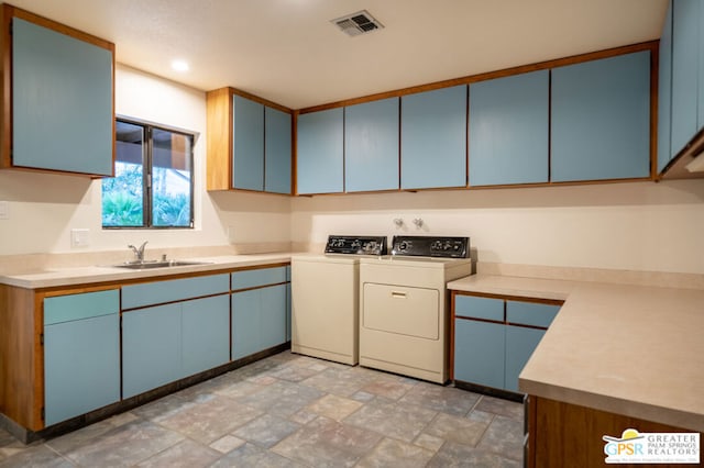 kitchen with washer and dryer, sink, and blue cabinetry