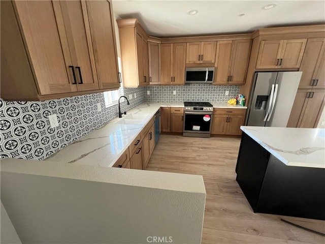 kitchen featuring light hardwood / wood-style floors, stainless steel appliances, tasteful backsplash, light stone countertops, and sink