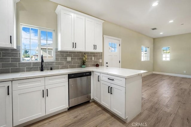 kitchen with light hardwood / wood-style floors, stainless steel dishwasher, kitchen peninsula, sink, and white cabinetry