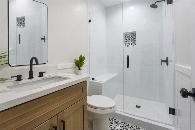 bathroom with toilet, vanity, and a shower with shower door