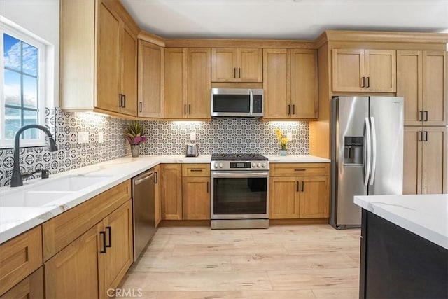 kitchen featuring decorative backsplash, sink, light wood-type flooring, stainless steel appliances, and light stone counters