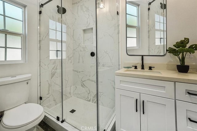 bathroom featuring a shower with shower door, toilet, and vanity