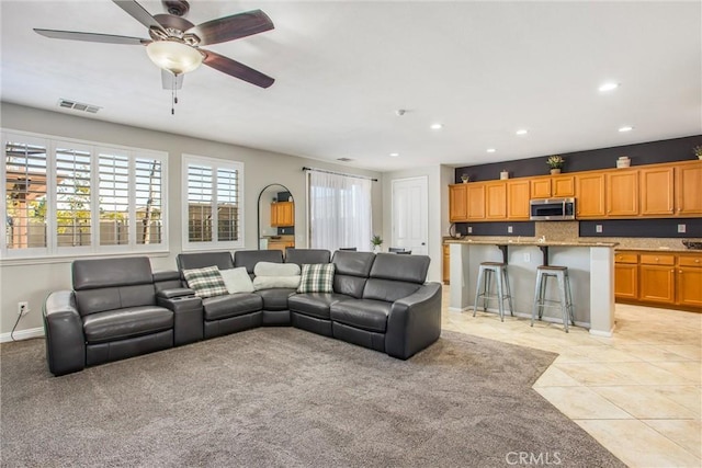 living room with light tile patterned floors, a wealth of natural light, and ceiling fan