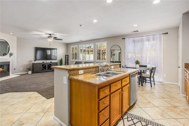 kitchen with a glass covered fireplace, light tile patterned floors, dishwasher, and a sink