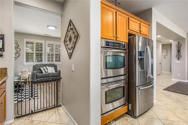 kitchen with light tile patterned floors, stainless steel appliances, and stone countertops