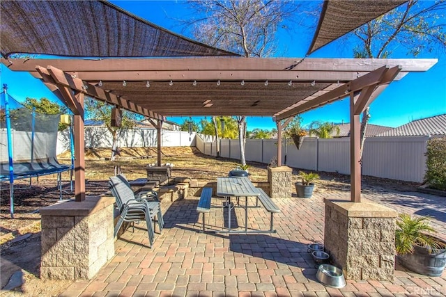 view of patio featuring a trampoline, a pergola, a fenced backyard, and outdoor dining space