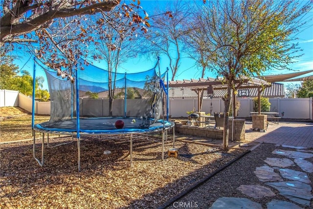 view of yard featuring a patio, a trampoline, and a fenced backyard